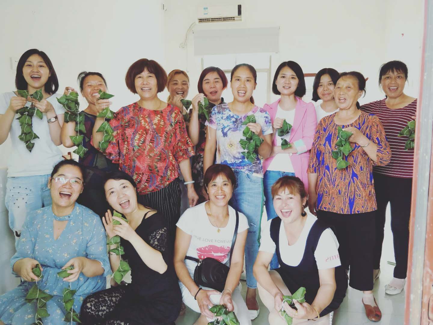 参赛选手和部分志愿者拧着亲手包的粽子，共享节日的快乐。.jpg